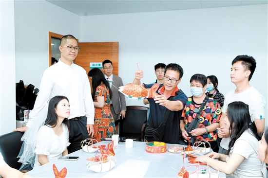 昨日，在新會(huì)區(qū)民政局婚姻登記處，工作人員向剛領(lǐng)證的新人們展示新會(huì)魚(yú)燈制作技巧。