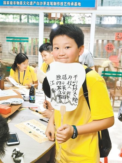 美國(guó)華裔青少年李恩誠用茅龍筆在扇面上寫下唐詩。