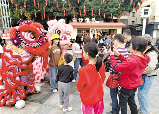 游客在長堤歷史文化街區(qū)與醒獅合影。何雯意