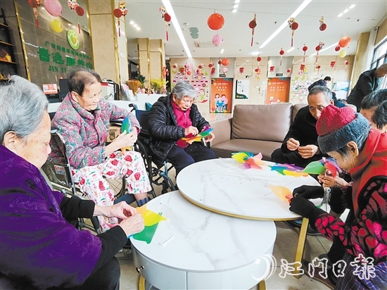 老人們圍坐在桌前，專(zhuān)注地制作小風(fēng)車(chē)。