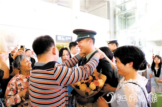 身著軍裝的返鄉(xiāng)退役士兵逐一出站，迎接他們的是鮮花與擁抱。