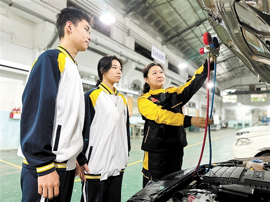 黃錚（右一）在汽修實(shí)訓(xùn)車(chē)間指導(dǎo)學(xué)生。