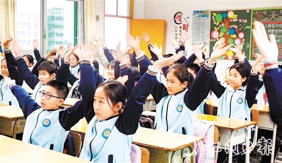 學生們在課桌前跟隨節(jié)奏做起“室內(nèi)課桌操”。