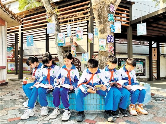 龍口鎮(zhèn)協(xié)華小學(xué)學(xué)生圍坐在“長滿書的大樹”下捧書共讀，成為該校一道亮麗的風(fēng)景線。