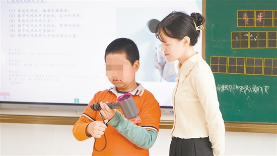 小明在老師指導(dǎo)下學(xué)習(xí)使用吹風(fēng)機(jī)。