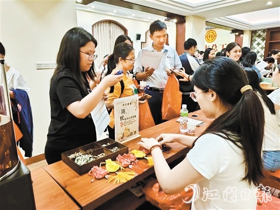 職工們與醫(yī)生探討中藥的成分和比例，制作防感驅蚊中藥香囊。