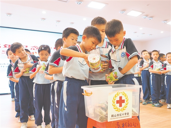 學(xué)生代表將愛(ài)心儲(chǔ)蓄罐里的零錢(qián)投入捐款箱，匯聚點(diǎn)滴愛(ài)心。