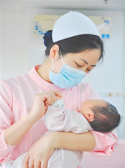 這是一雙托起生命的手。江門市中心醫(yī)院愛嬰?yún)^(qū)主管護(hù)師湯玲玲正在安撫哭鬧的寶寶。她一手環(huán)住襁褓，一手牽起寶寶的小手，動(dòng)作舒緩而溫柔。在這里，生命的啼哭與溫柔的守護(hù)相遇，匯聚成世間至暖的力量。（林錦棠