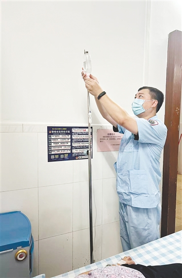 吳益浩核對(duì)藥液、為患者調(diào)整輸液流速。