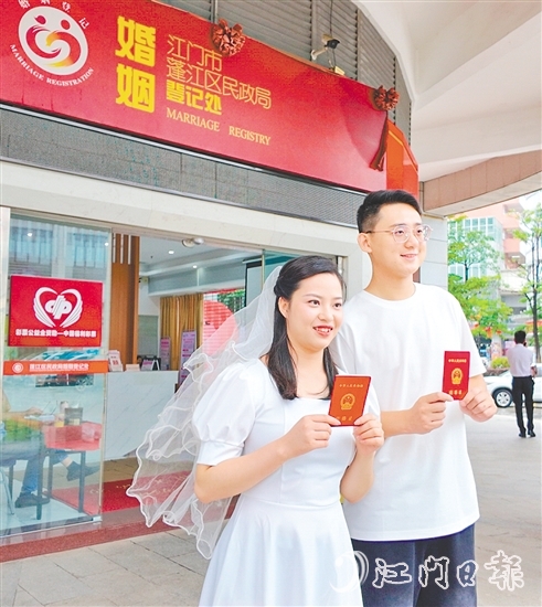 一對(duì)新人在蓬江區(qū)民政局婚姻登記處門(mén)口合影留念。