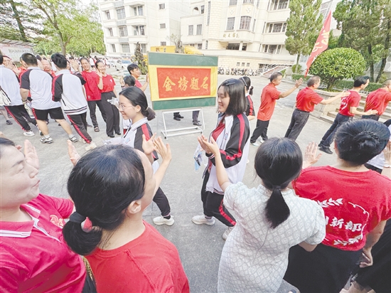 臺山一中在送考路上設(shè)置了“金榜題名”大字帖，教師身穿紅衣與學(xué)生擊掌，為學(xué)生加油。