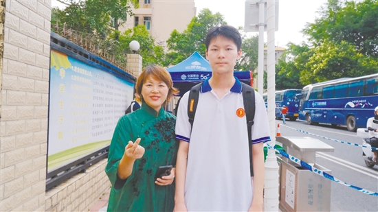 身著綠色旗袍的李女士與兒子合影。
