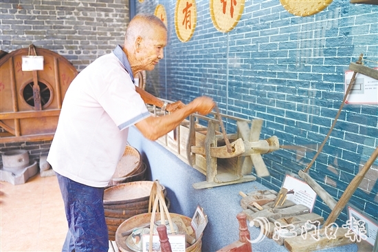新華村打造農(nóng)耕文化展館，留住鄉(xiāng)村記憶。圖為村中老人向記者介紹農(nóng)具。
