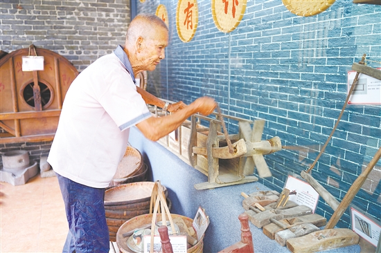 新華村打造農(nóng)耕文化展館，留住鄉(xiāng)村記憶。圖為村中老人向記者介紹農(nóng)具。