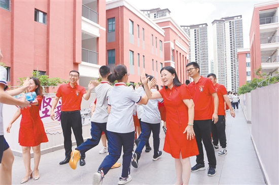蓬江區(qū)紫茶中學(xué)的領(lǐng)導(dǎo)和老師們與考生們擊掌，為他們加油、鼓勁。