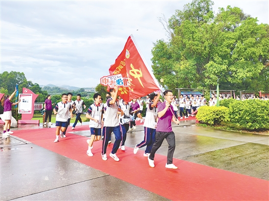 在臺山市武溪中學(xué)，老師揮舞著“中考加油”的紅旗為考生加油助威。