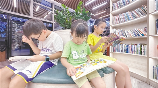 低年級學(xué)生圍坐在書架旁閱讀繪本。