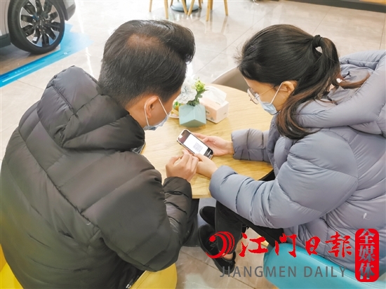 新能源汽車銷售人員協(xié)助車主用手機進行投保新能源汽車險。